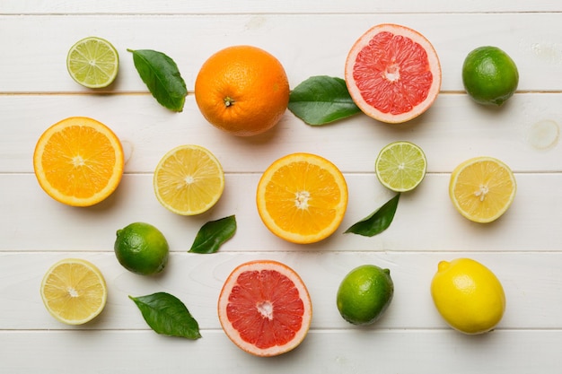 Flat lay of citrus fruits like lime orange and lemon with lemon tree leaves on light colored background Space for text healthy concept Top view