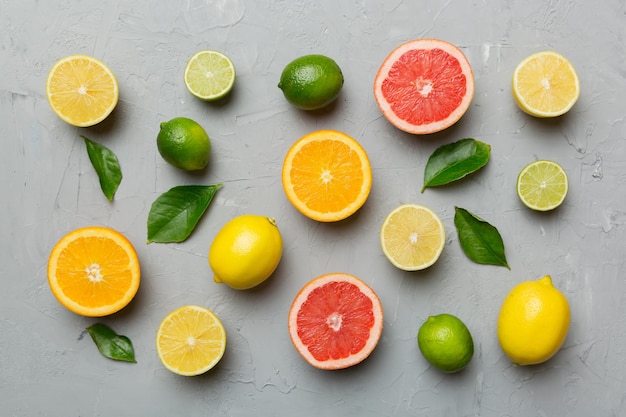 Flat lay of citrus fruits like lime orange and lemon with lemon tree leaves on light colored background Space for text healthy concept Top view