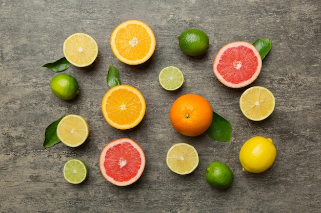 Flat lay of citrus fruits like lime orange and lemon with lemon tree leaves on light colored background Space for text healthy concept Top view