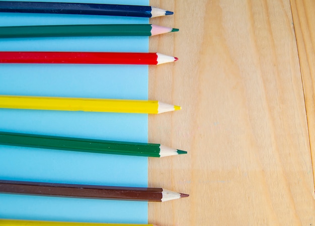 Flat lay, colored pencils, blue and wooden background, back to school, copy space