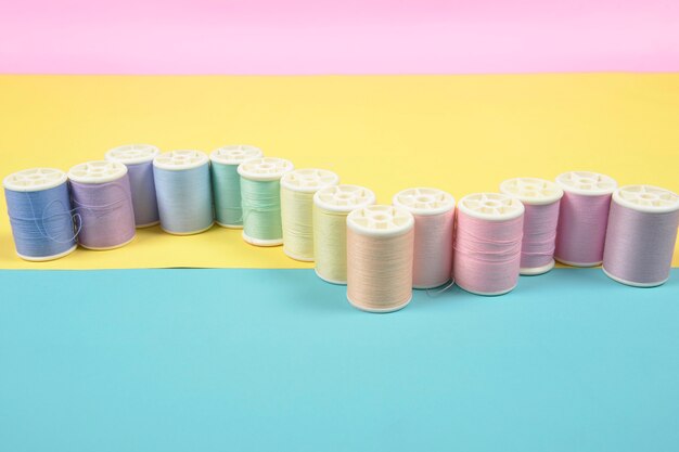 Flat lay of colored thread rolls for sewing on two tone background.