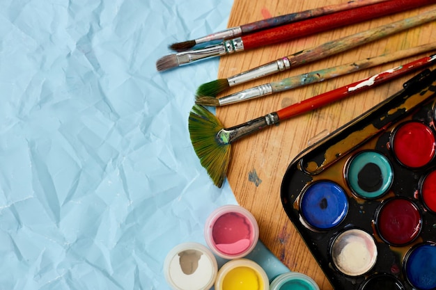 Flat lay of colorful paints painting palette and brushes