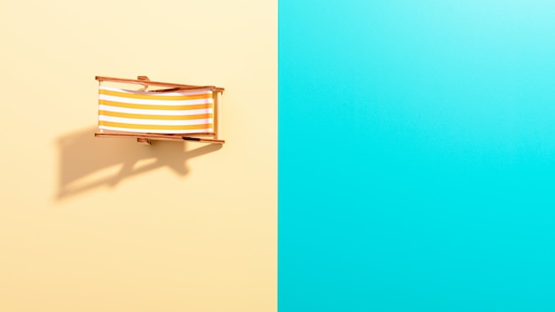 Flat lay of a composed miniature of beach lounge area with deck chair on the colorful surface