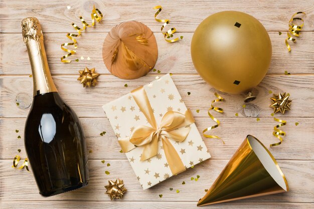 Flat lay composition of Champagne bottle gift box ribbons and confetti on colored background Flat lay top view holiday concept