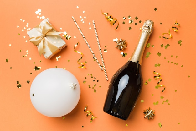 Flat lay composition of Champagne bottle gift box ribbons and confetti on colored background Flat lay top view holiday concept