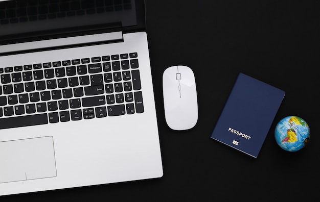 Flat lay composition of laptop and travel accessories on black background. Tourism. Top view.