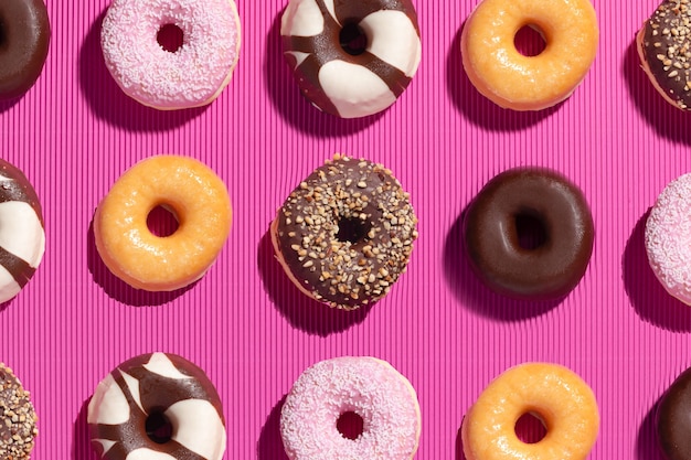 Flat lay composition of mixed donuts on pink background.