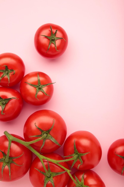 Flat lay composition with bunch of tomatoes on pink background Vertical photo