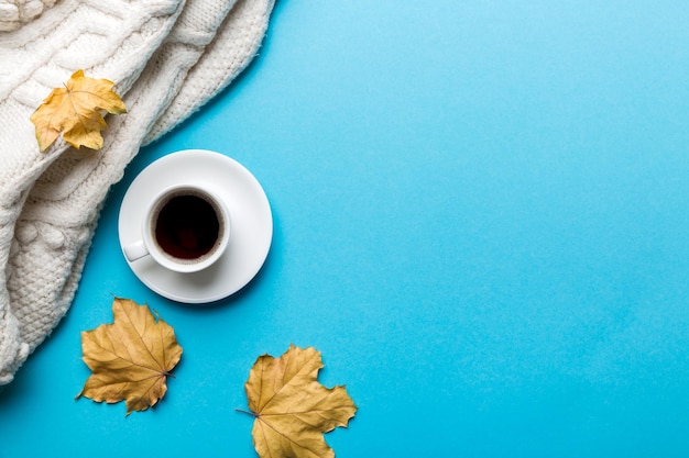 Flat lay composition with colorful Autumn cup of coffee and leaves on a color background top view