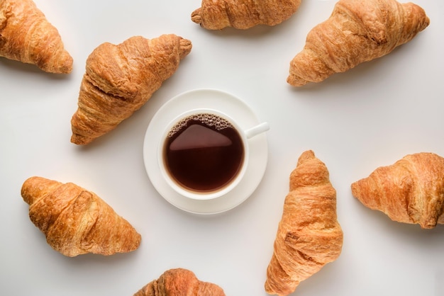 Flat lay composition with a cup of coffee and croissants on a white background