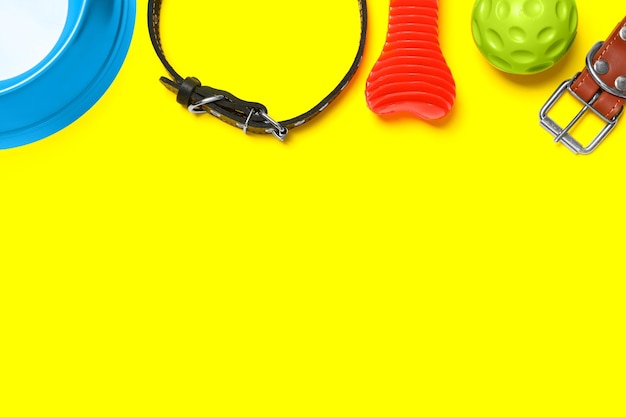 Flat lay composition with dog collar and toys on yellow background Space for text