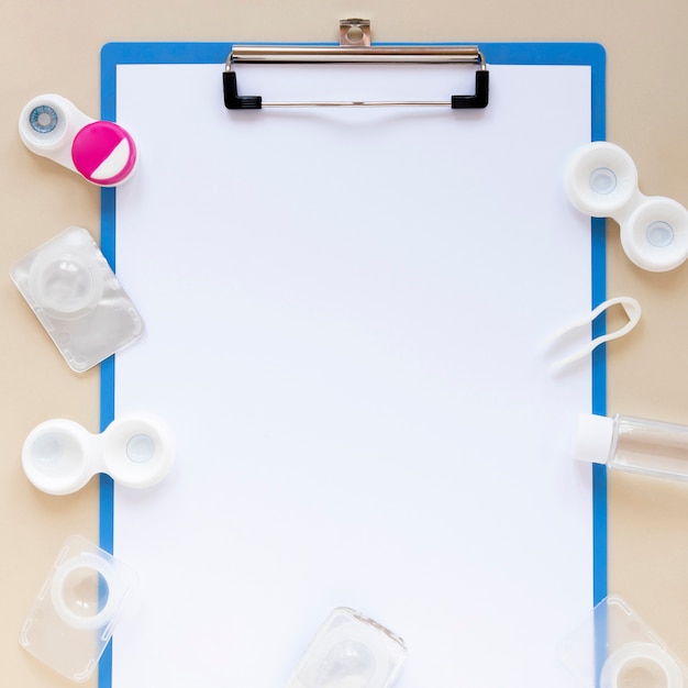 Flat lay composition with empty clipboard and lenses