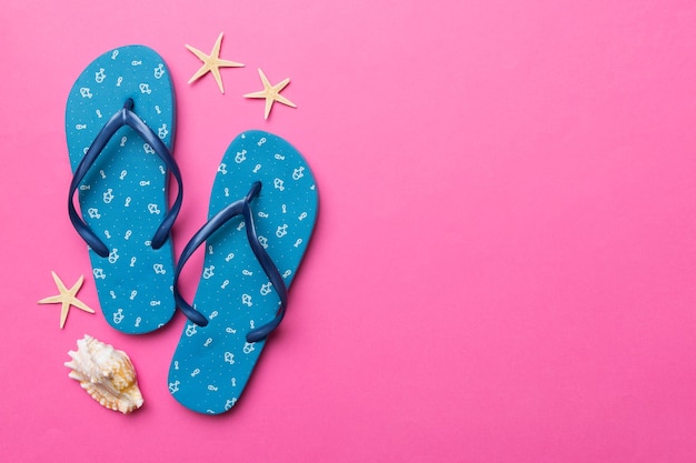 Flat lay composition with flip flops and seashell on colored background Space for text top view