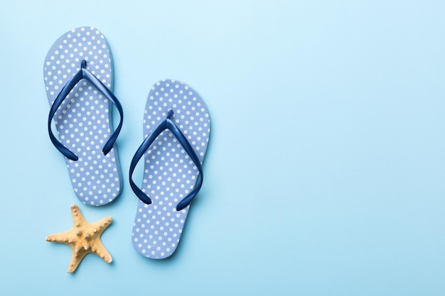 Flat lay composition with flip flops and seashell on colored background Space for text top view