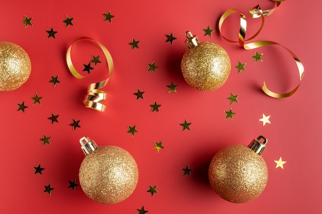 Flat lay composition with gold serpentine streamers and Christmas baubles on red background