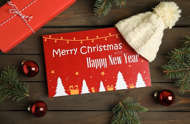 Flat lay composition with greeting card and Christmas decor on wooden background