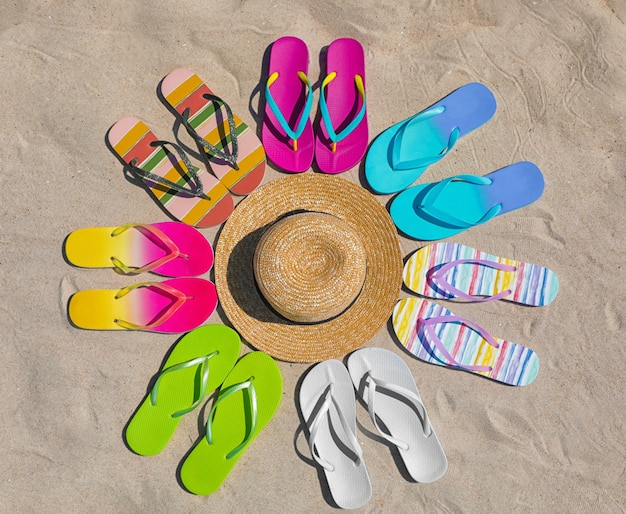 Flat lay composition with hat and flip flops on sand Summer beach accessories