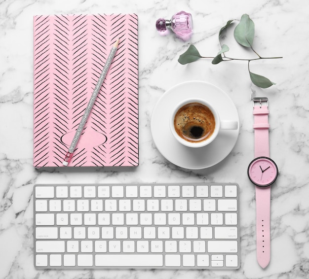 Flat lay composition with keyboard coffee and notebook on white marble background