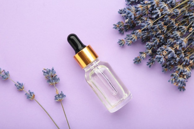 Flat lay composition with lavender flowers and lavender oil on purple background