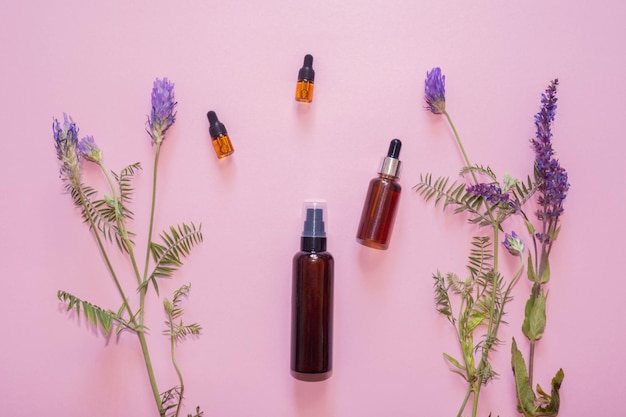 Flat lay composition with lavender flowers and natural cosmetics on a pink background. View from above