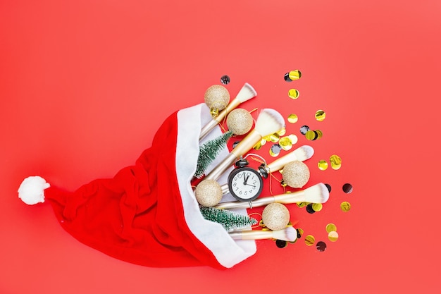 Flat lay composition with makeup brushes and Christmas decor on red paper background.