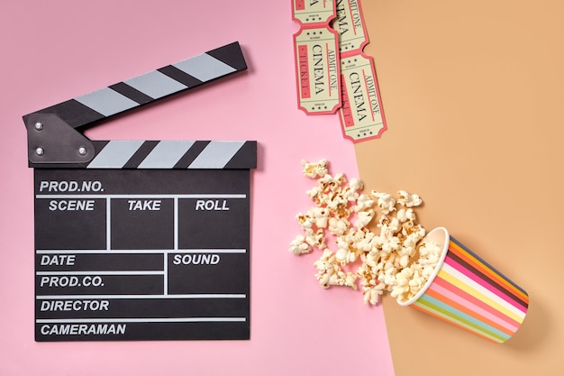 Flat lay composition with popcorn, tickets and clapper board, space for text on color surface