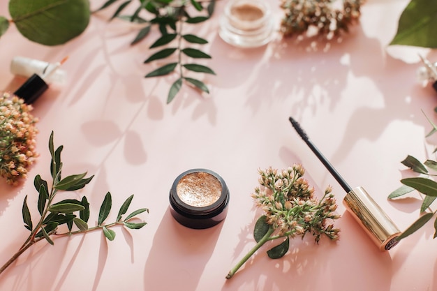 Flat lay composition with products for decorative makeup on a pink table.