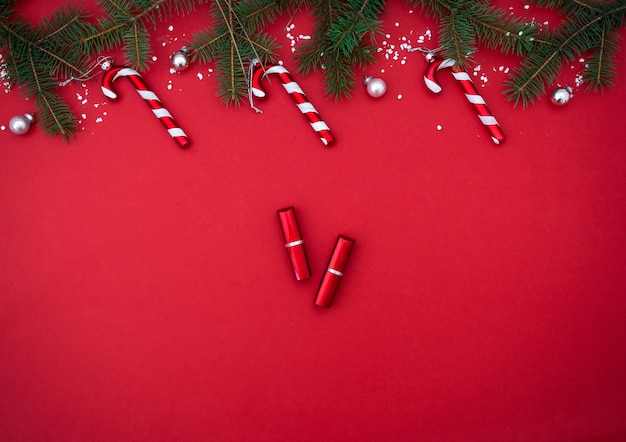 Flat lay composition with red lipstick and Christmas decor on red background Top view Beauty banner