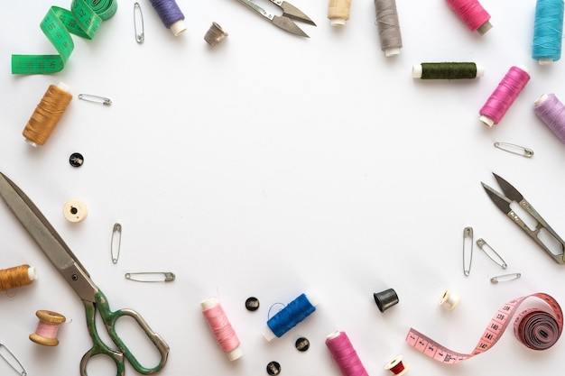 Flat lay composition with scissors and other sewing accessories on white background. Space for text