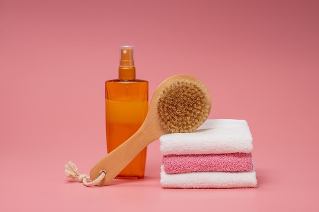 Flat lay composition with spa cosmetics and towel on pink background