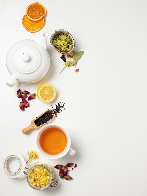 Flat lay a cup of black tea, fruit and herbal tea, with lemon and tea pot on a white background. The concept of a healthy drink. Top view and copy space.