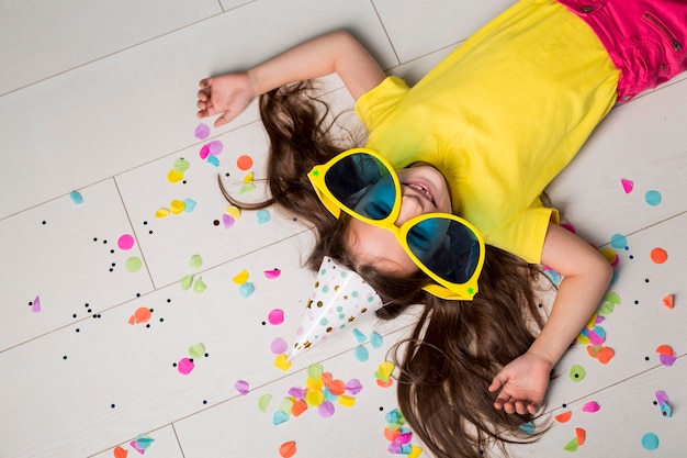 Flat lay of cute little girl with big sunglasses