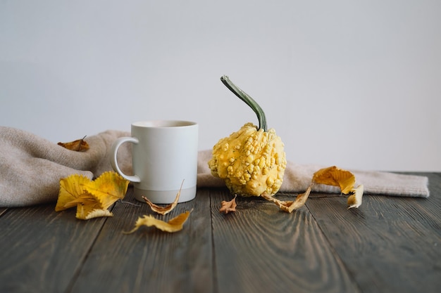 Flat lay of decorative pumpkins dried leaves accessories and tea with lemon in cup on wooden background Top view copy space Autumn concept