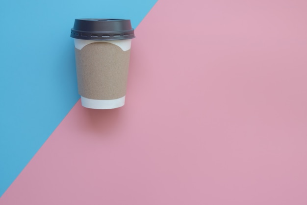 Flat lay design of hot coffee cup with blank cardboard for your brand  on pink and blue pastel.