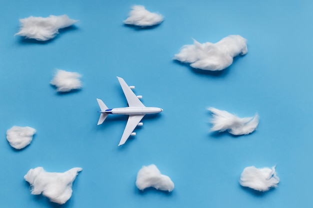 Flat lay design of travel concept with plane and cloud on blue