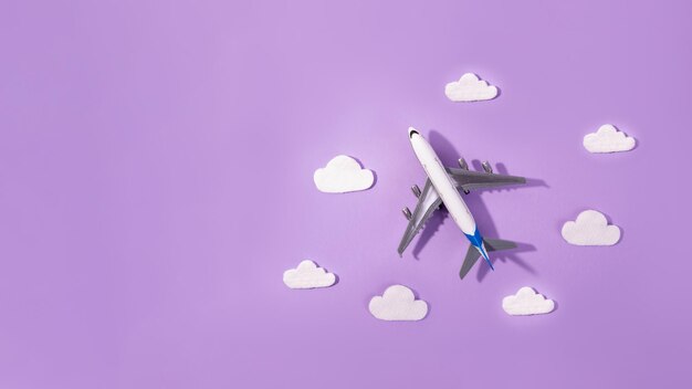 Flat lay design of travel concept with plane and cloud on purple Small airplane model toy