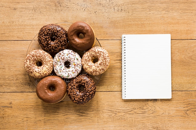 Flat lay of donuts on plate with notebook