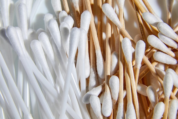 Flat lay Ecofriendly wooden bamboo and plastic cotton swabs sticks for cleaning ears on white background copy space