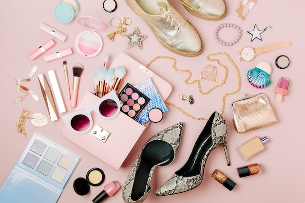 Flat lay of female fashion accessories makeup products and handbag on pastel color background