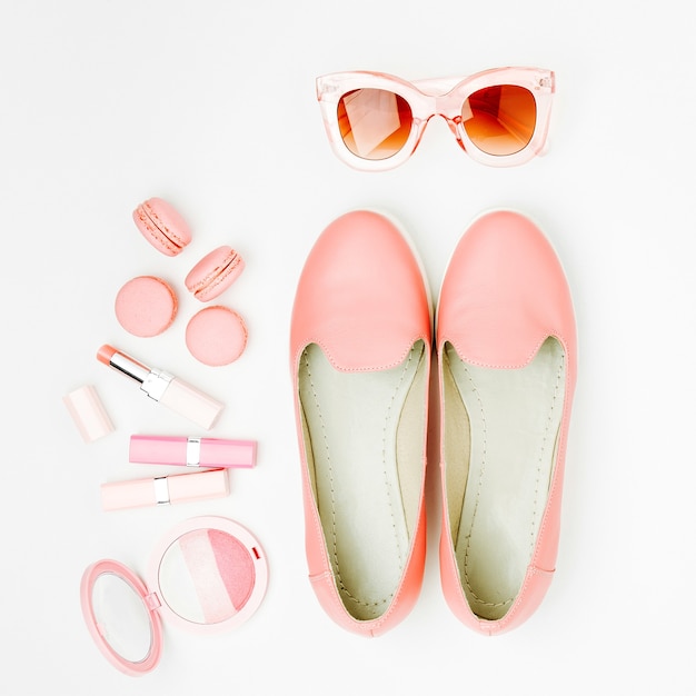 Flat lay of female fashion accessories, shoes, makeup products  on pastel color background. Beauty and fashion concept