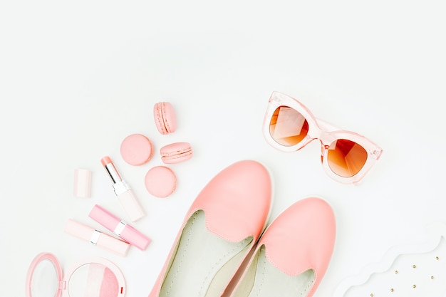 Flat lay of female fashion accessories, shoes, makeup products  on pastel color background. Beauty and fashion concept