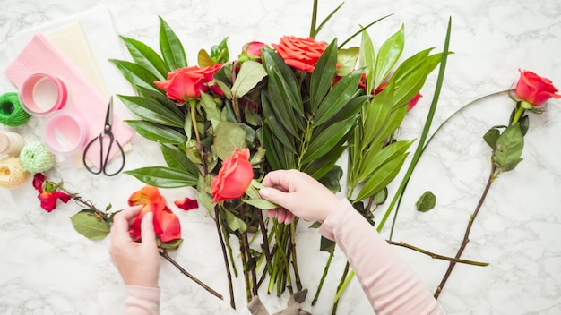 Flat lay. Florist pruning red roses for bouquet arrangement.