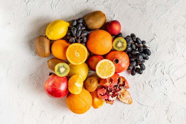 Flat lay fresh fruit selectrion layout on a grunge surface such as grapes, kiwi, orange, exotic tropical fruit