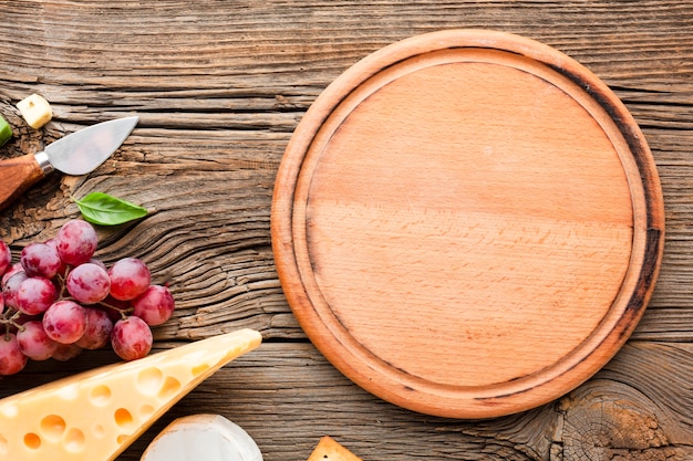 Photo flat lay grapes emmental and cheese knife with wooden cutting board