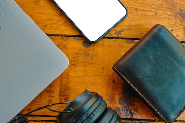 Flat lay of headphones smartphone and leather wallet on wooden table freelancers work surface mobile...