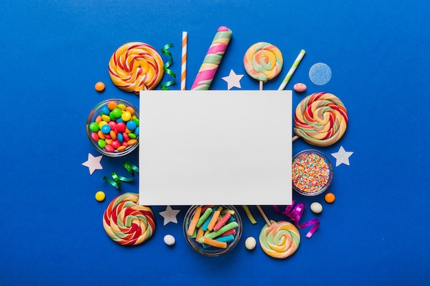 Flat lay holiday composition Paper blank lollipop birthday decorations on Colored background Top view copy space for text