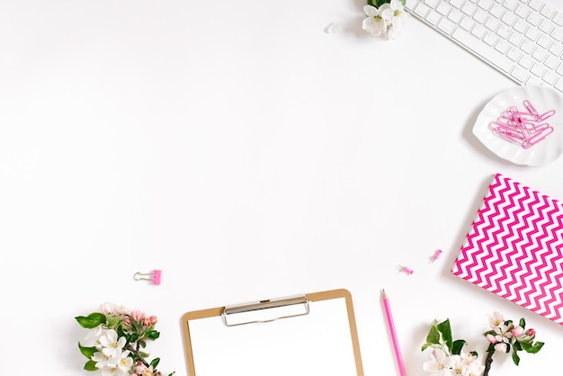 Flat lay home office workspace female blogger background with white modern keyboard notebook and apple flowers copy space on white background