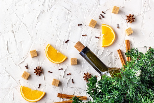 Flat lay of ingredients for Mulled wine. Bottle of wine, orange, sugar, cinnamon sticks, anise and fir branches. Top view with copy space