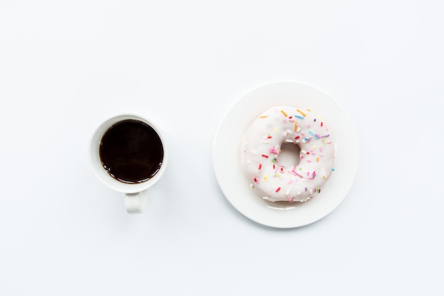 Flat lay items: coffee cup and donut lying on white background