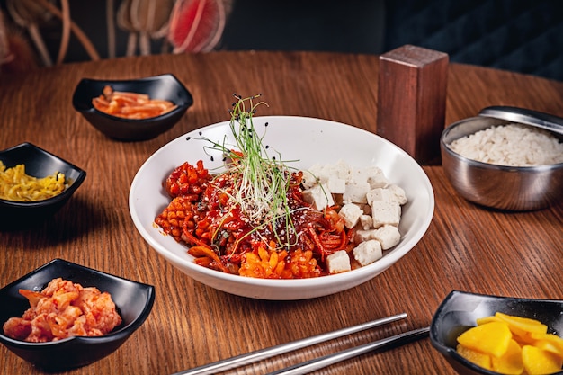 Photo flat lay korean traditional food with kimchi on wooden background. korean noodles with onions, red sauce and sesame, chicken meat. traditional asian cuisine. lunch. healthy food